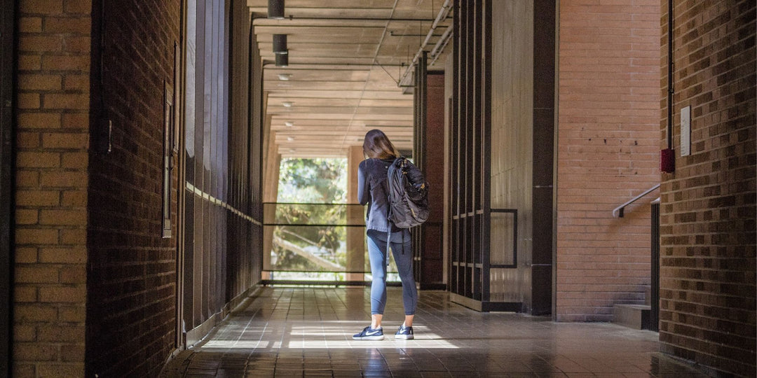 A college student walks down a long corridor.