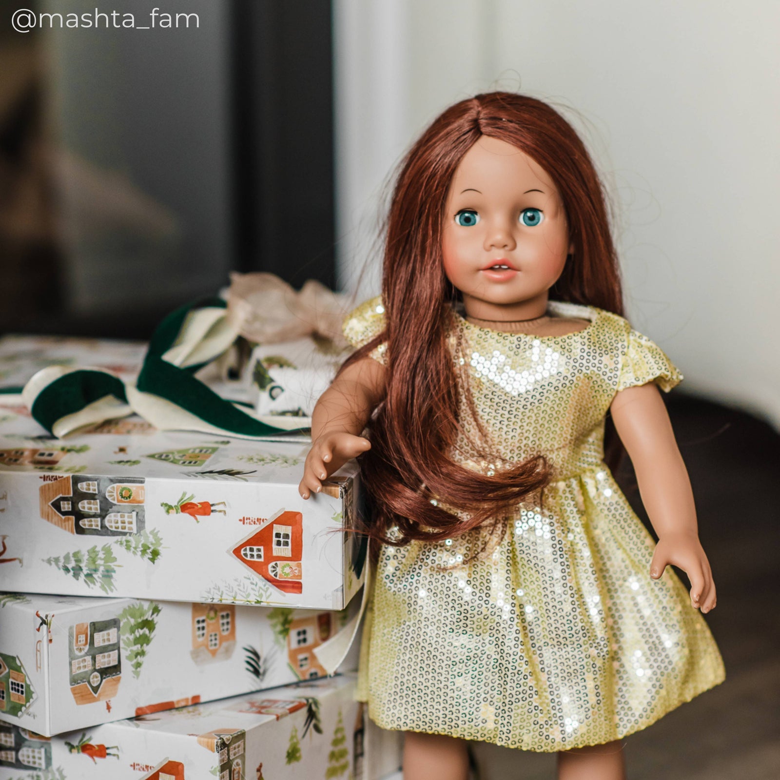 A doll wearing gold dress standing next to gift boxes