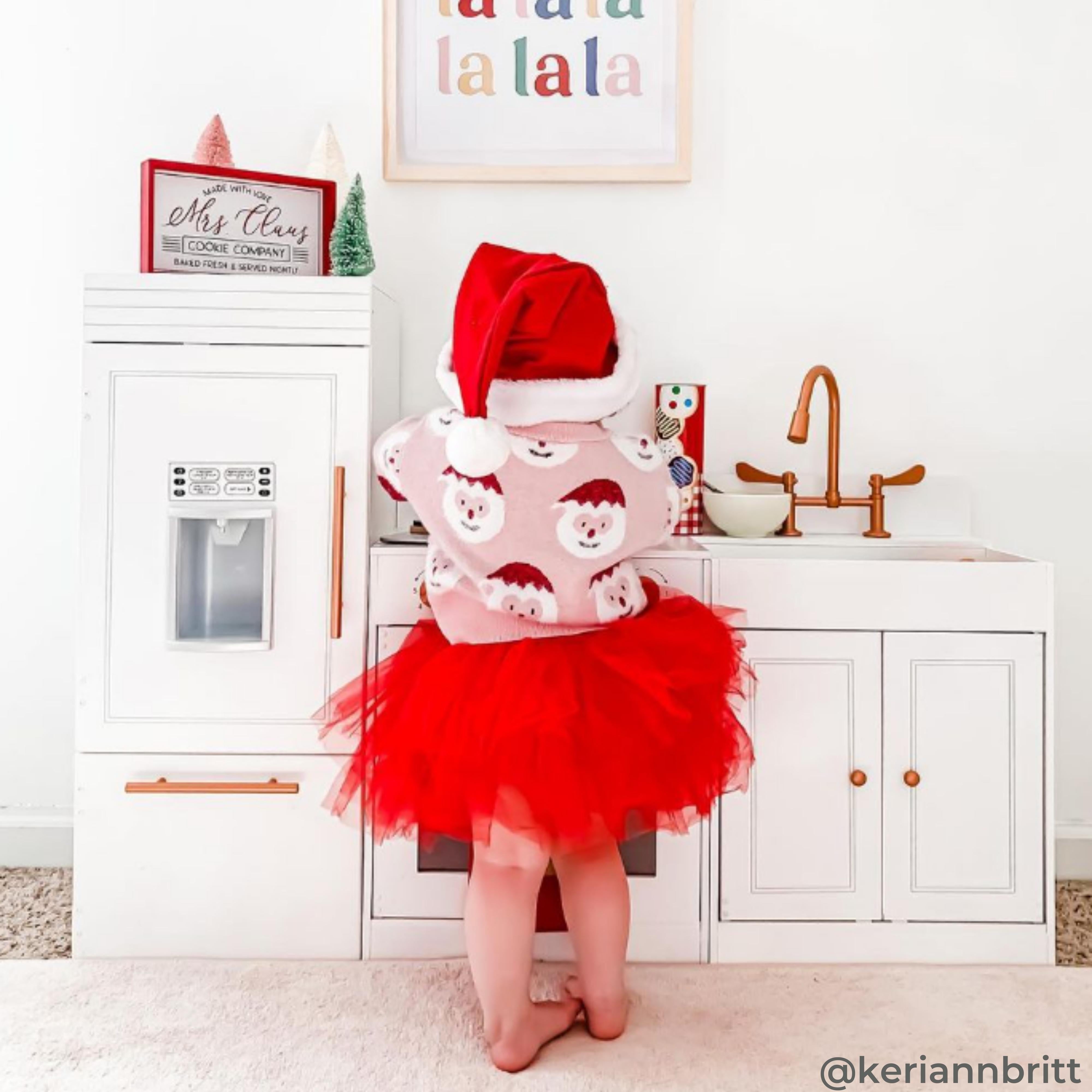 A girl is playing with a white play kitchen