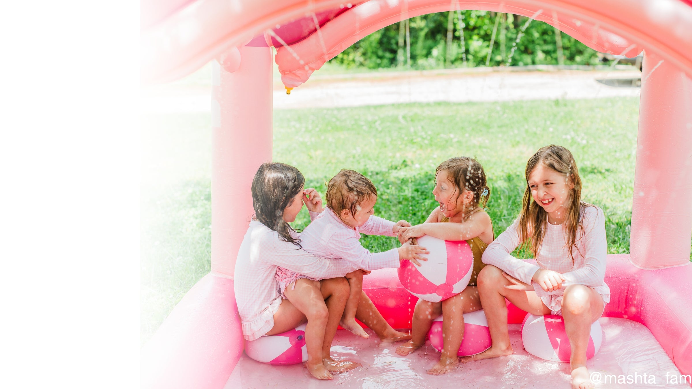 four young girls play together in the pink castle kiddie pool sprinkler