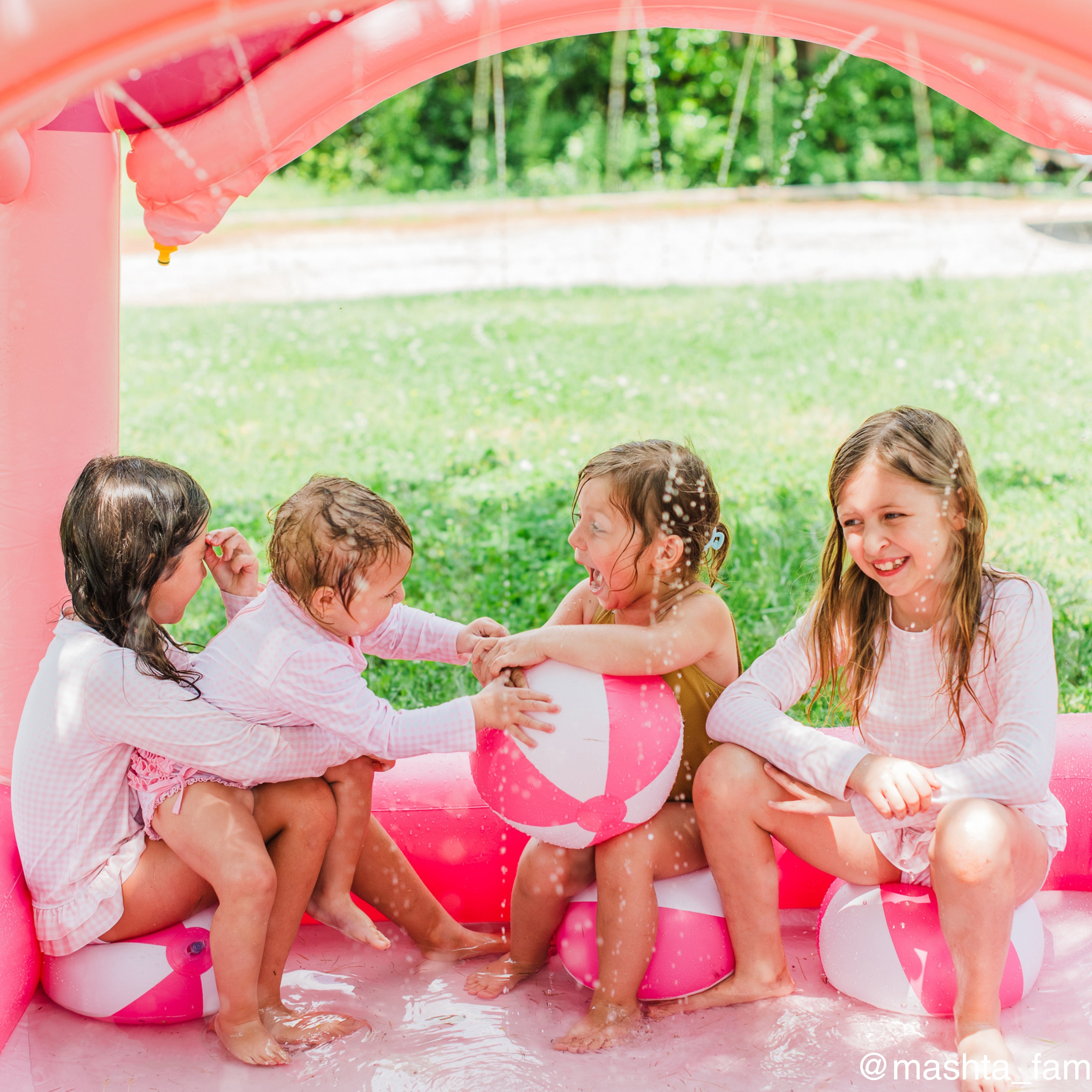 four young girls play together in the pink castle kiddie pool sprinkler
