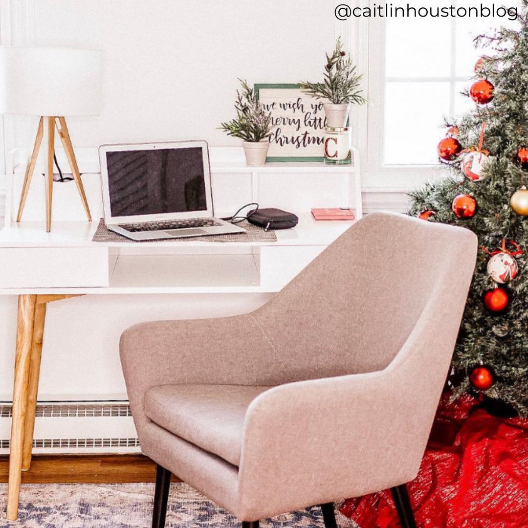 A grey chair in front of a white desk, next to a Christmas tree