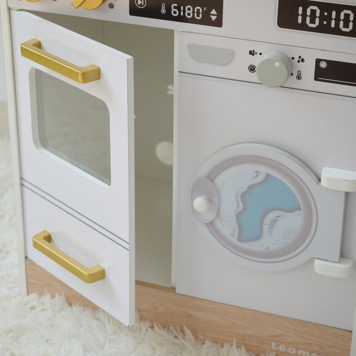 Close-up of play kitchen with oven door open and washer featuring a printed water design, set on a soft white rug.