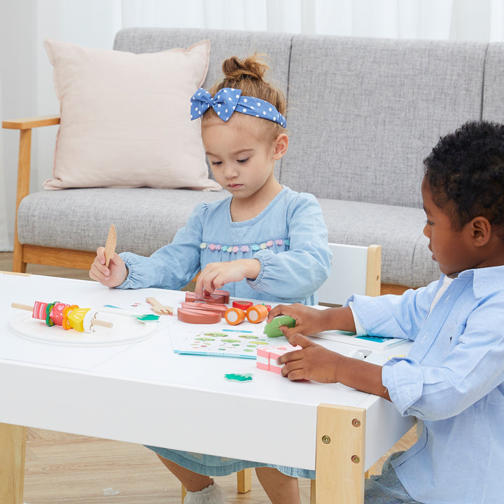 Two kids play at a table with the wooden food