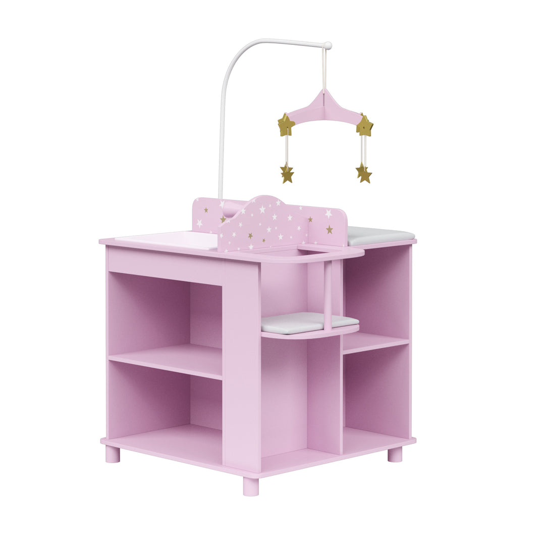 Pink toy doll changing table with shelves and a star-themed mobile attached.