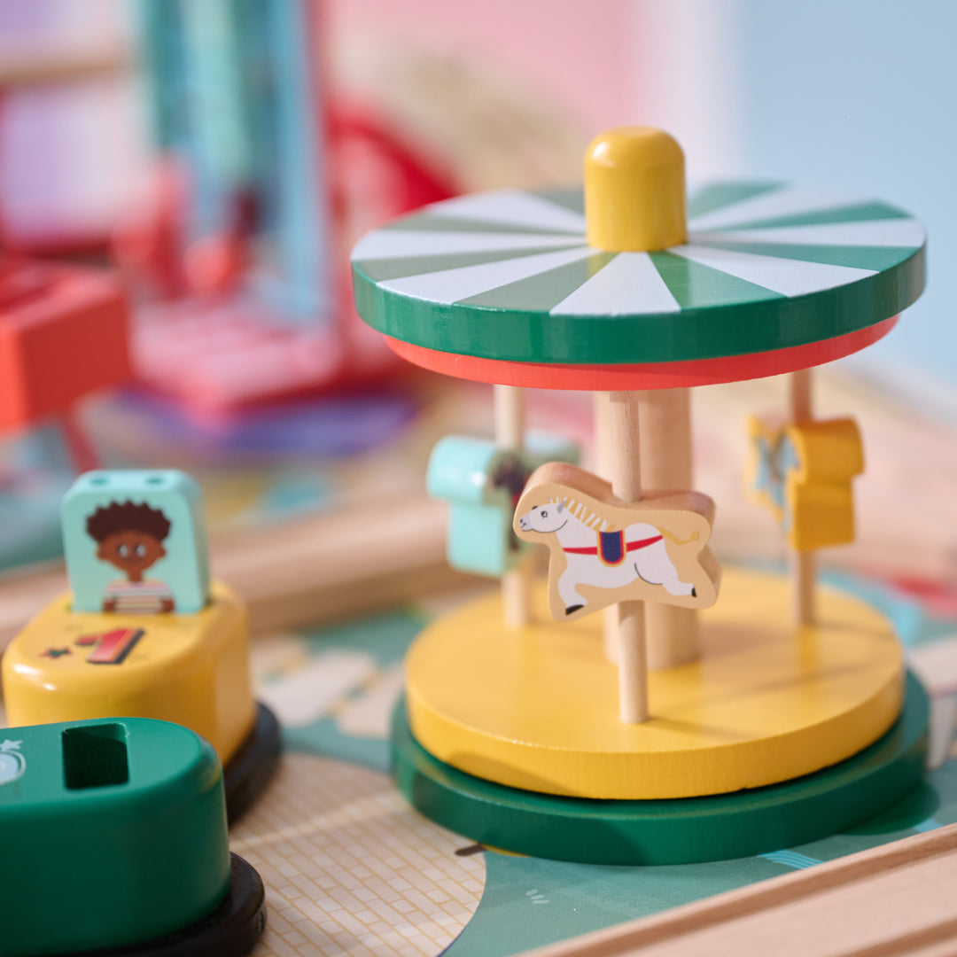 Wooden carousel with horse figures and nearby ticket booths in a playset.