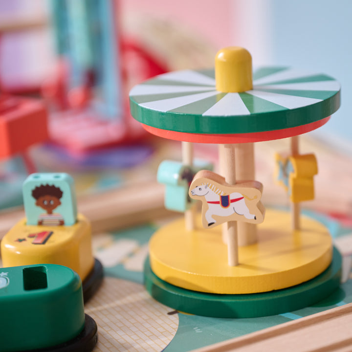 Wooden carousel with horse figures and nearby ticket booths in a playset.