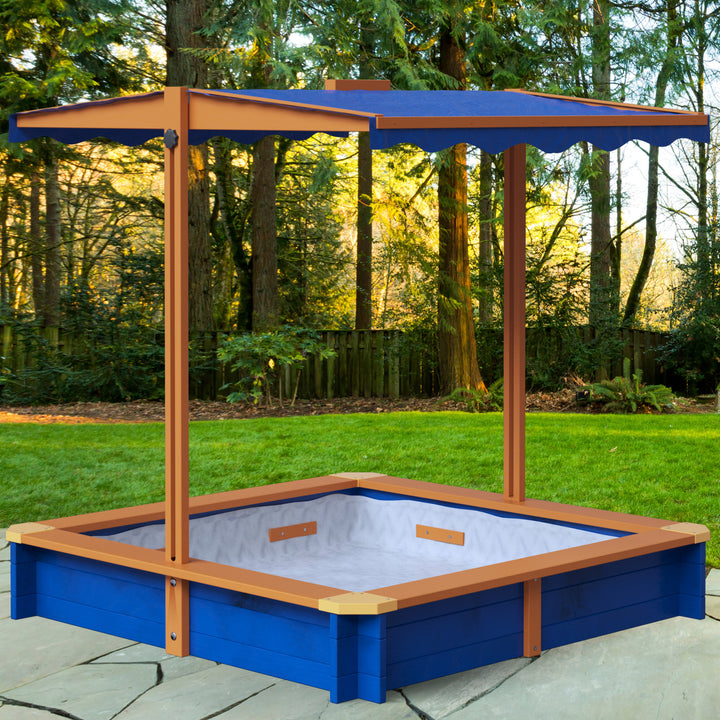 A blue and wood-toned sandbox with a blue awning in a backyard