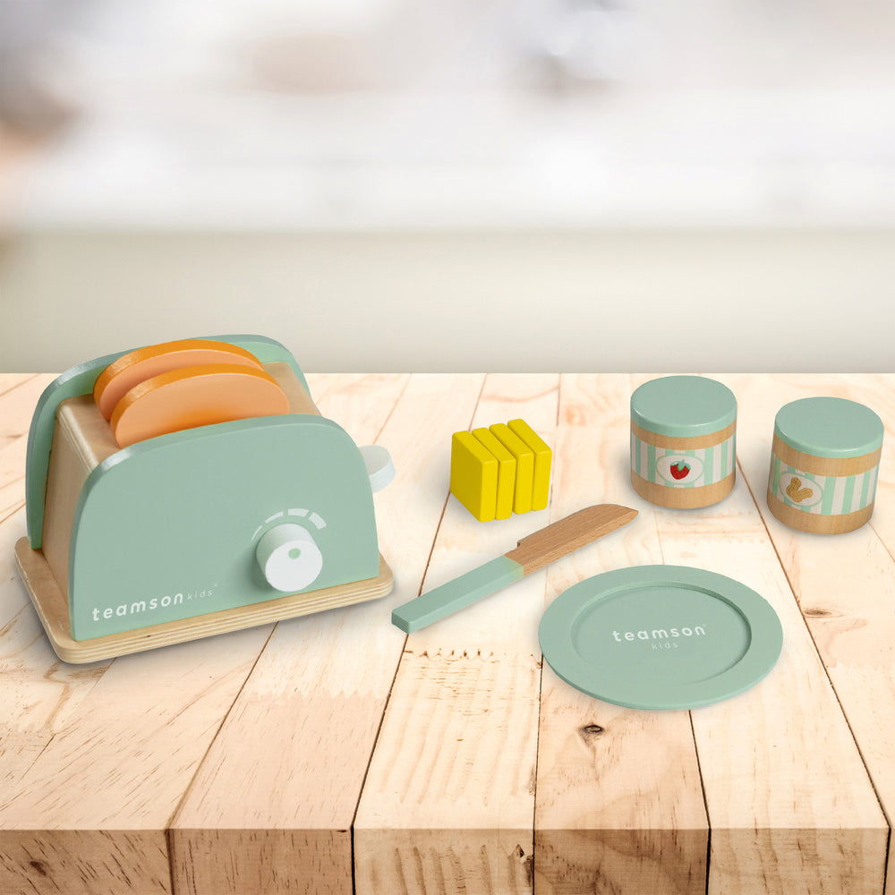 A play toaster with pretend bread, butter pats, knife, jars of spread and a plate