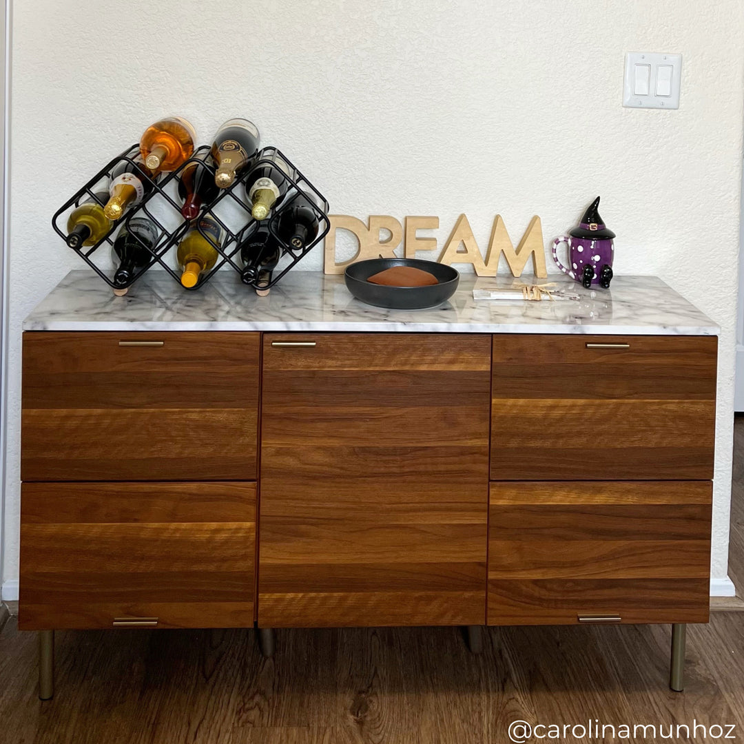 A sideboard with faux marble tabletop with a wine rack and other seasonal decor