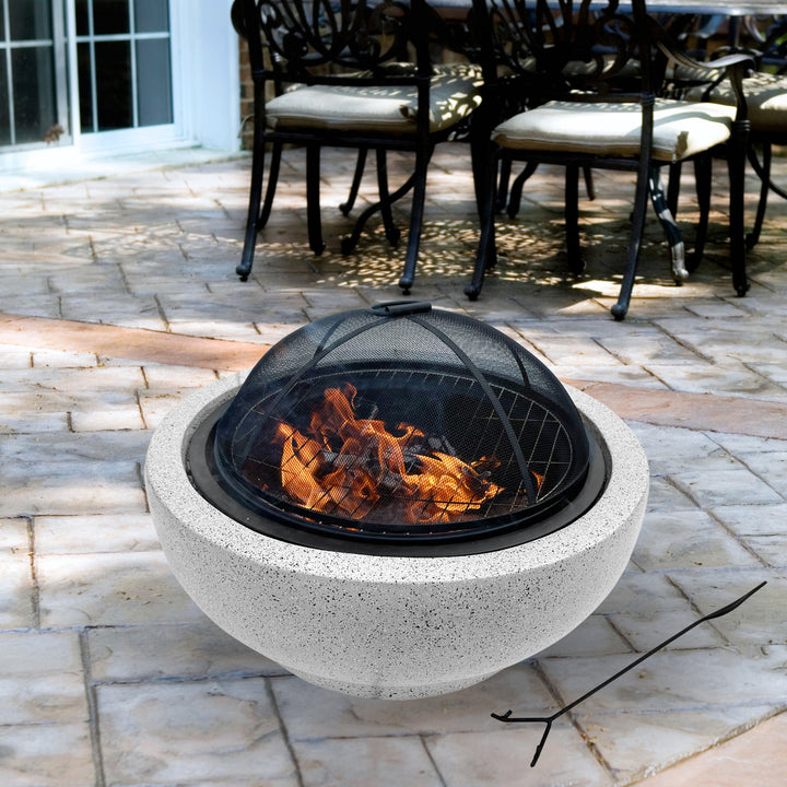 The fire pit shown on a patio with chairs, fire glowing.