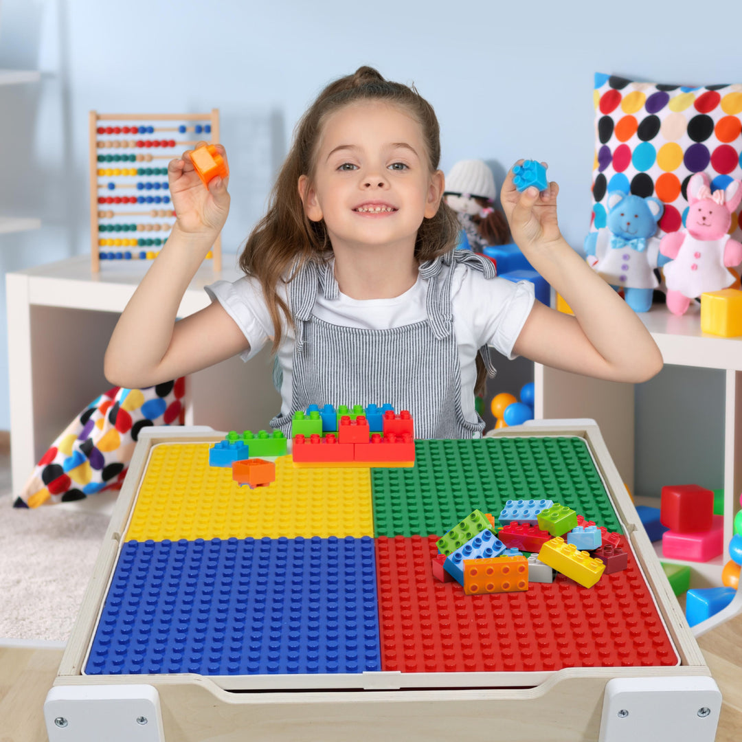 A girl building something on top of building surface with assorted building blocks.