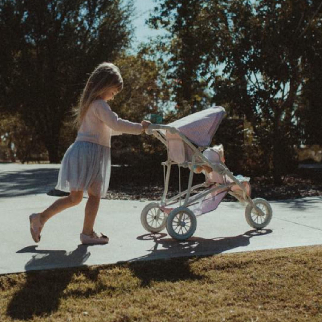 A photo of a girl pushing a tandem jogging stroller outside