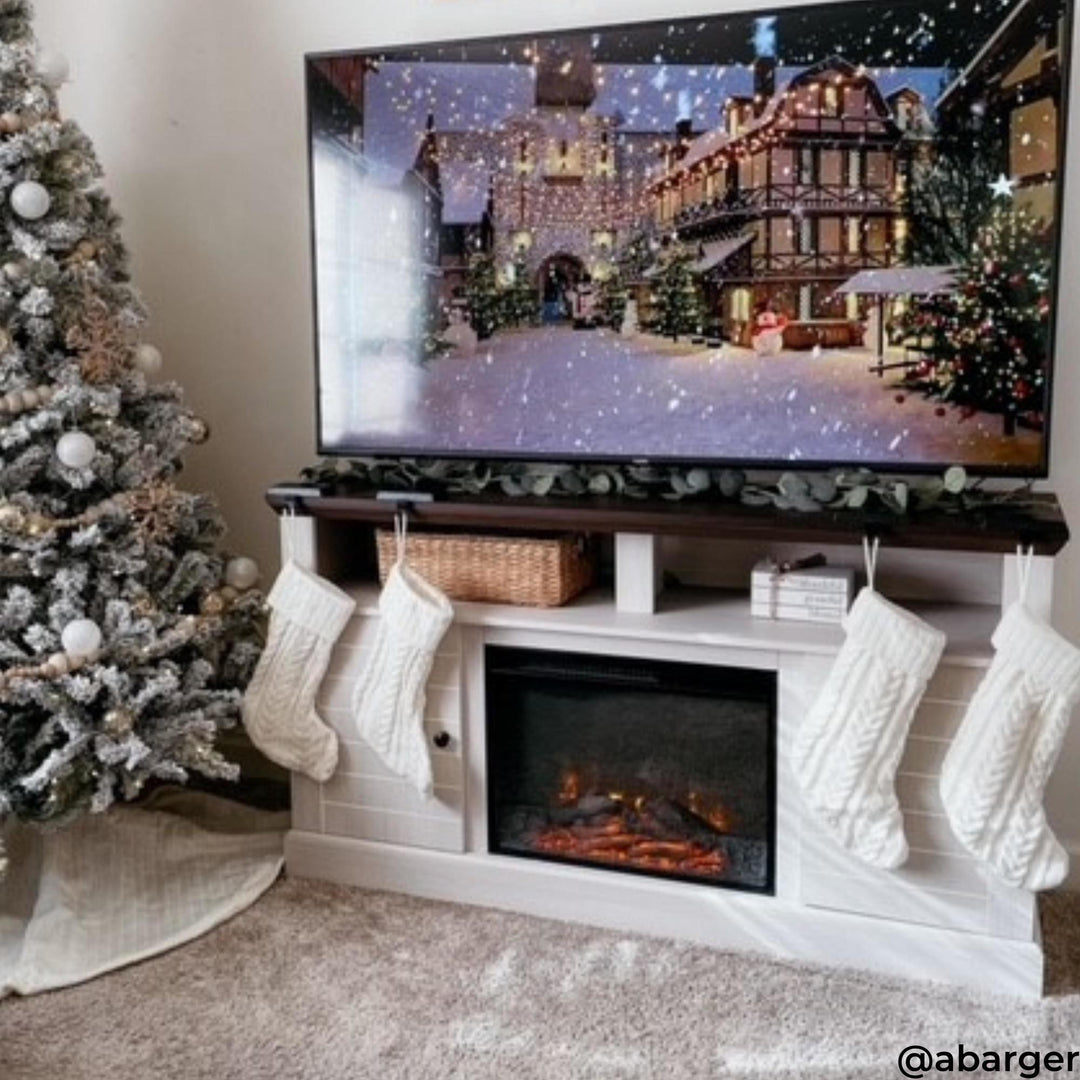 A white entertainment center with electric fireplace in a christmas setting