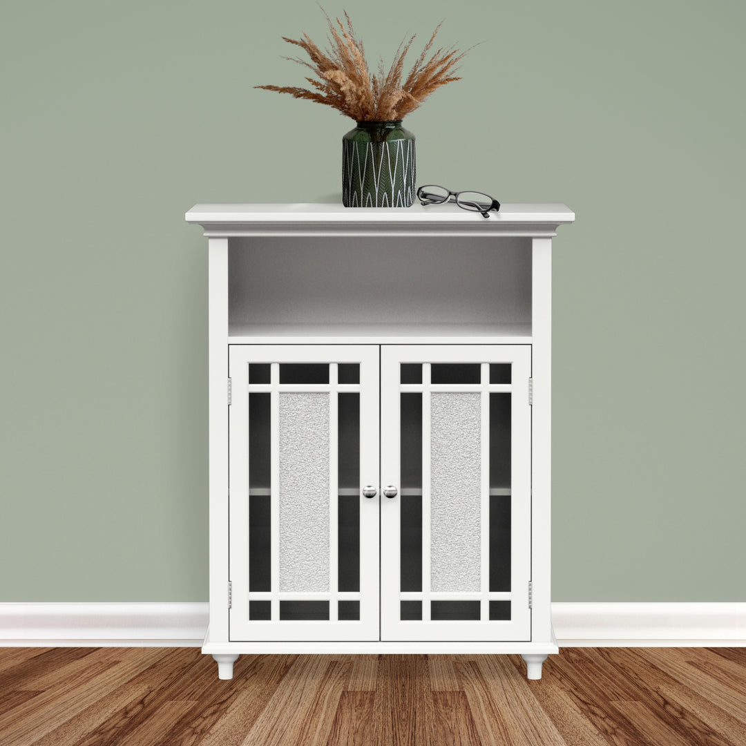 A white floor cabinet against a sage green wall with decor on top