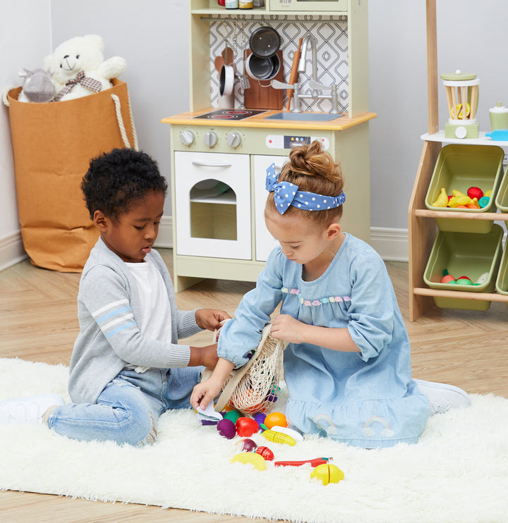 Two young kids empty out the net bag to see all of their produce.