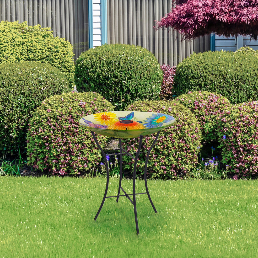 Lifestyle image of the yellow birdbath with butterflies and flowers.