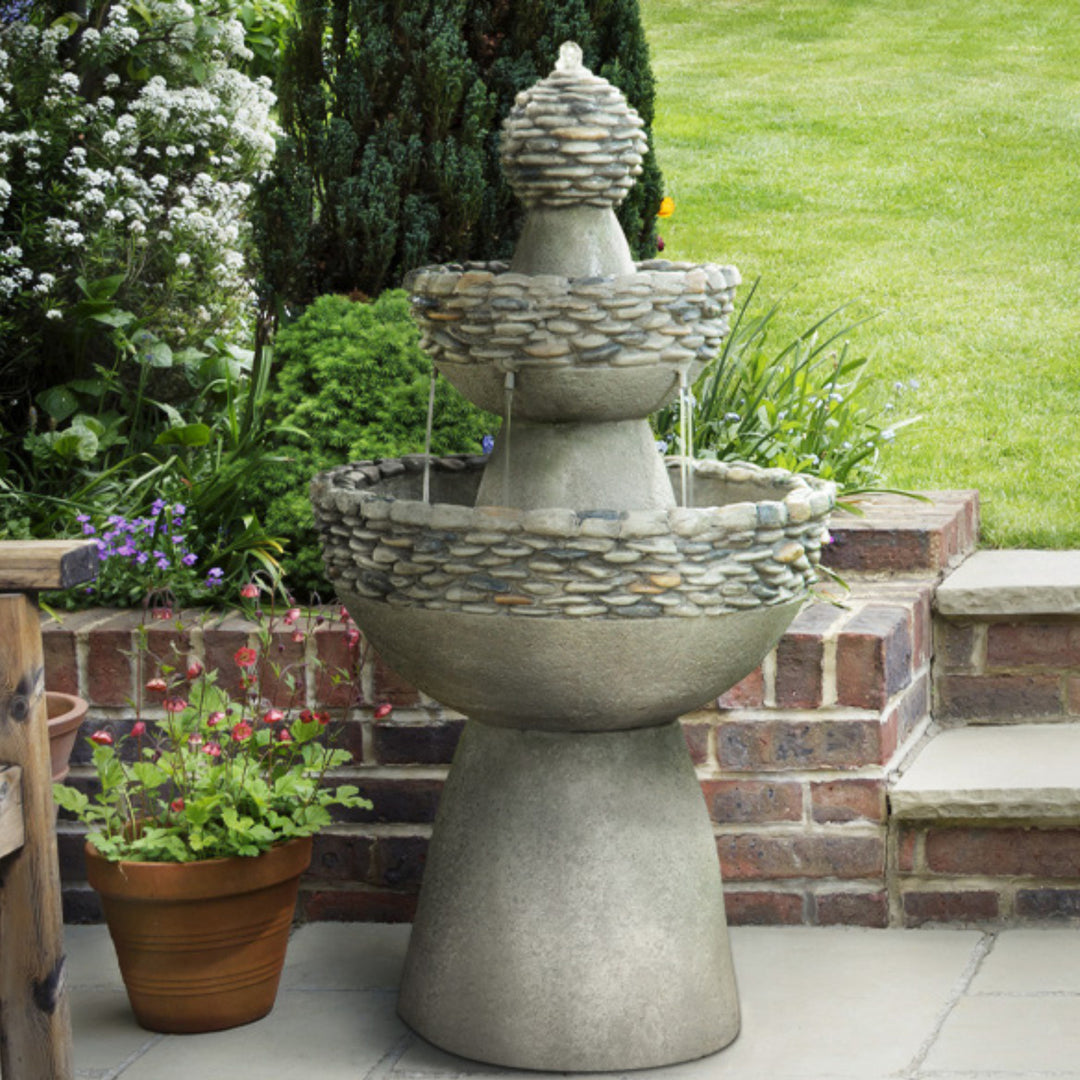 3-tiered birdbath style water fountain with pebble accents in a garden setting