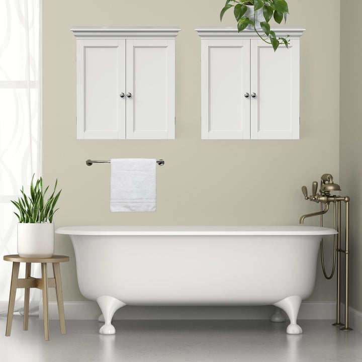 Two white wall cabinets hung above a bathtub in a sage green bathroom