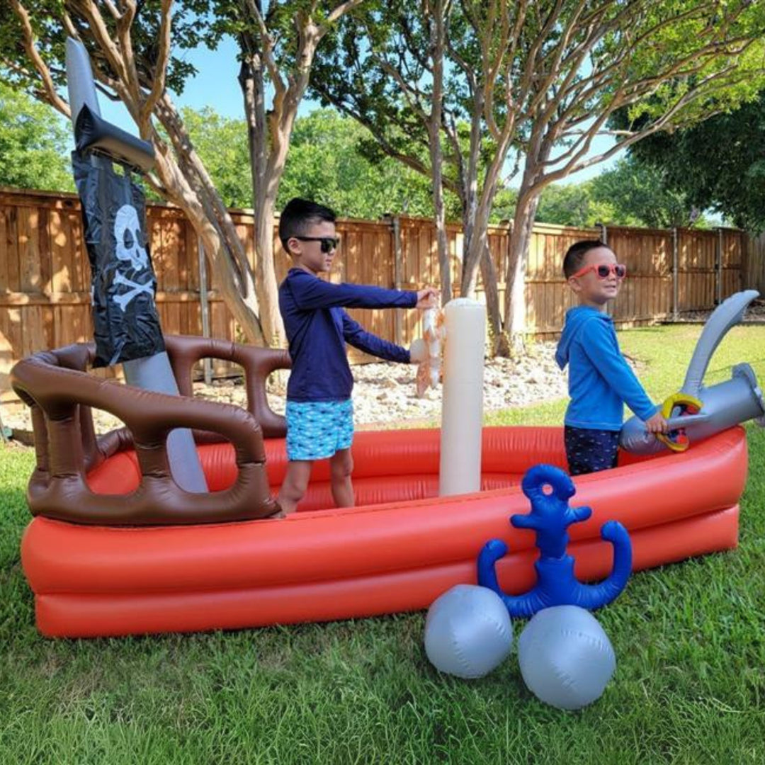 Two boys inside an inflatable pirate ship in a back yard