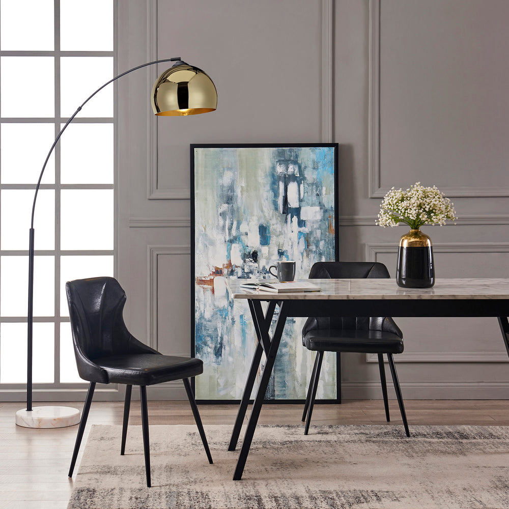 Lifestyle image of the arc lamp, black leather chairs sitting around a faux marble table top in a dining room.