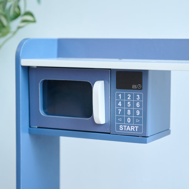 Close-up of toy microwave with keypad, white handle, part of a blue wooden play kitchen set.