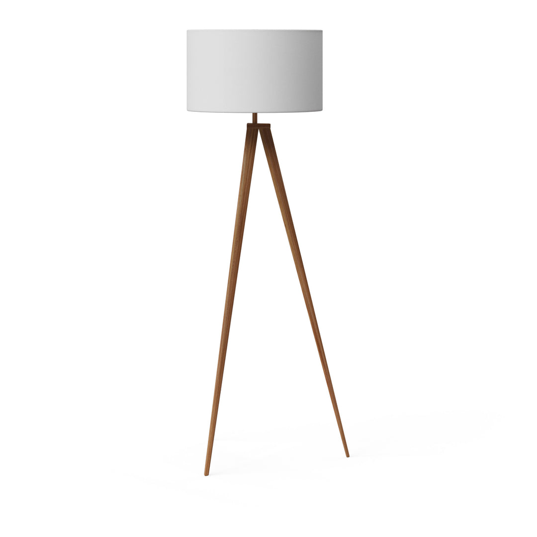 A tripod style floor lamp with natural wood finished legs and a white faux linen lampshade