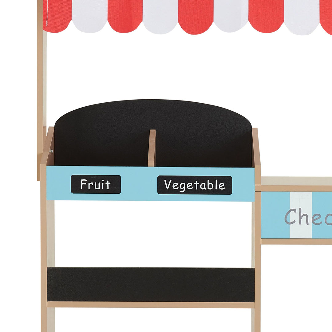 A farmer's market stand with a red and white striped awning with bins for play food.