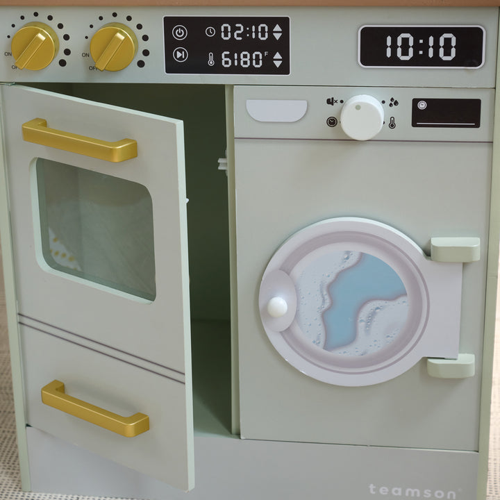 Close-up of green kitchen-laundry playset with oven door open and washer door featuring a printed water design.