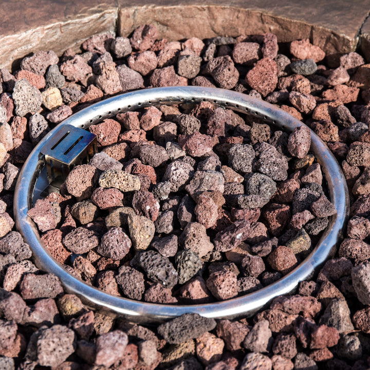 Closeup of a gas fire pit ring in the middle of some lava rocks