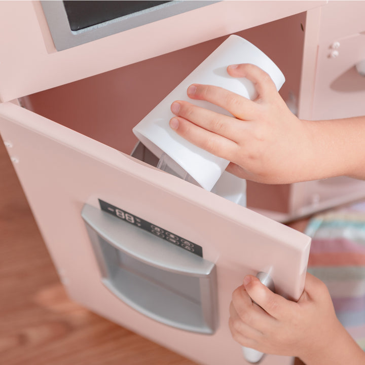 Child opening a Teamson Kids Little Chef Westchester Retro Play Kitchen, Pink microwave door, part of a kids play kitchen set with interactive features.