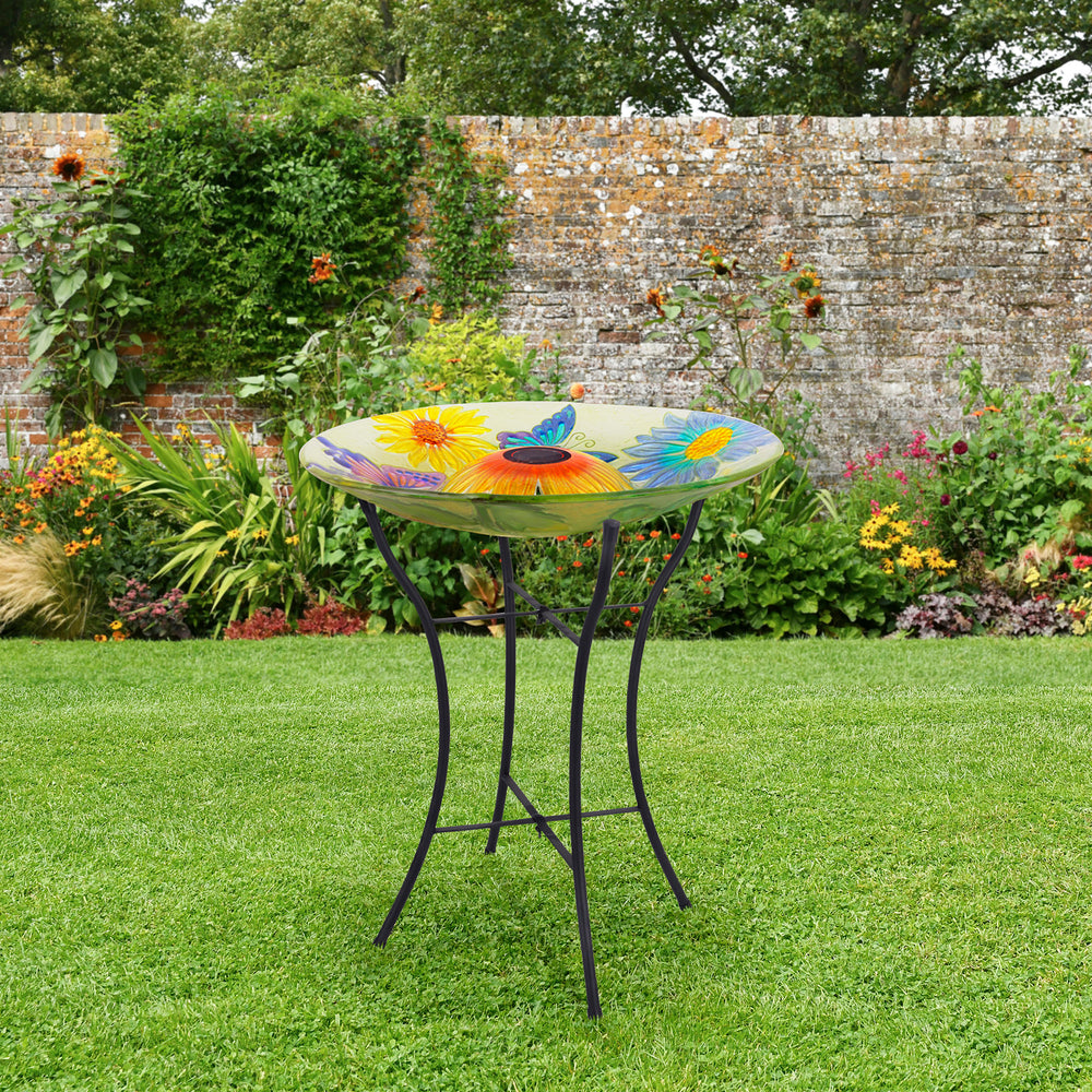 Lifestyle image of the yellow birdbath with butterflies and flowers in a garden