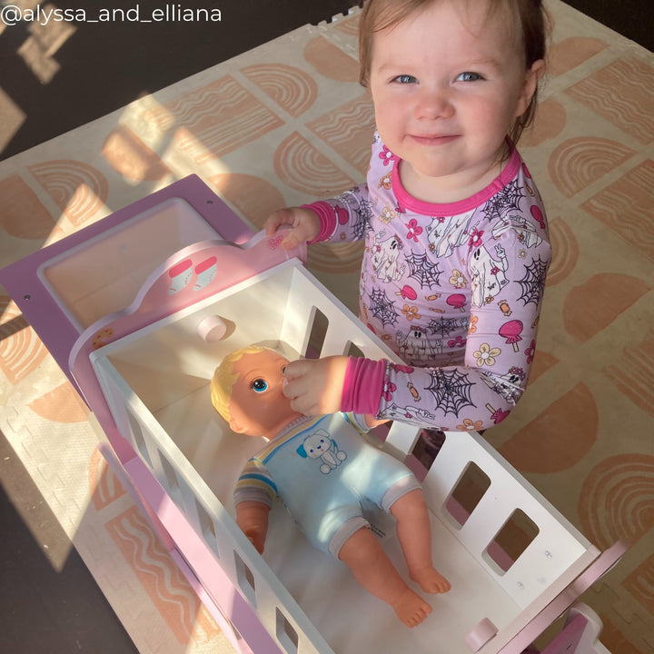 A little girl playing with a baby doll in a cradle
